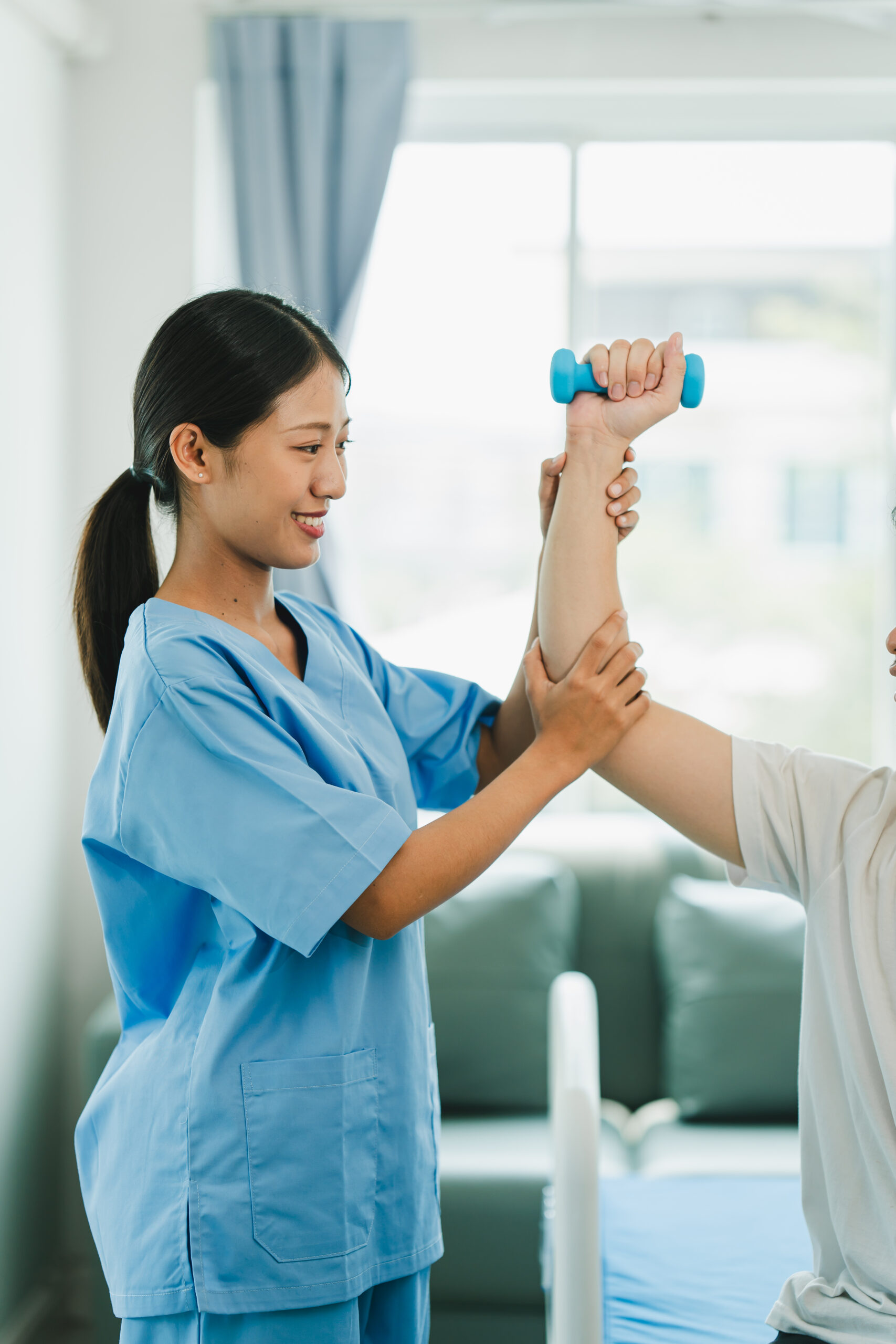 Physical therapist giving exercise by maintaining dumbbells on the arms and shoulders of a male patient. Physical therapy concept